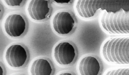 Phononic crystal etched in a silicon wafer. The 100 micron deep air holes run vertically, defining a honeycomb-lattice artificial crystal for acoustic waves